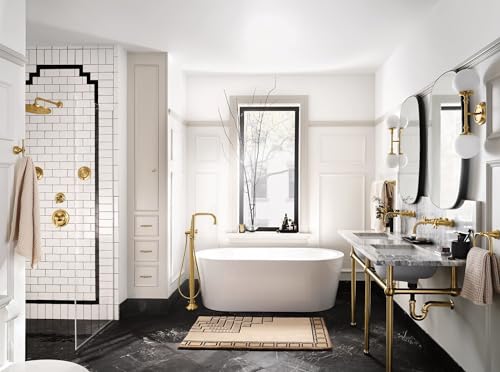 Brushed gold freestanding tub filler with handshower positioned beside white soaking tub in modern bathroom.
