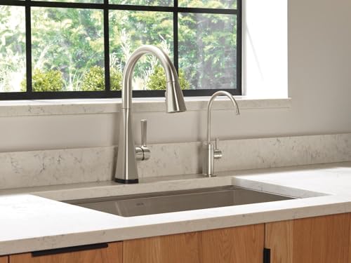 Stainless steel Delta Clarifi beverage faucet with curved spout installed next to kitchen sink.