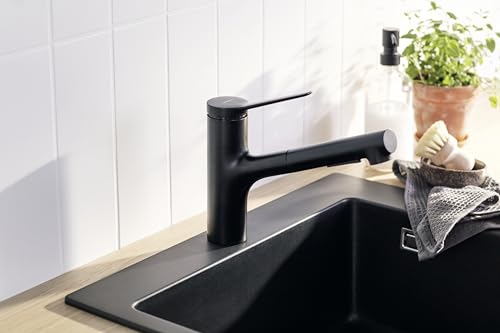 Matte black kitchen faucet with single lever handle and pull-out spray nozzle mounted on sink countertop.