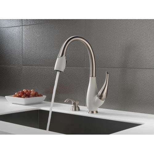 Stainless steel soap and lotion dispenser with white accents mounted on white countertop next to kitchen sink.