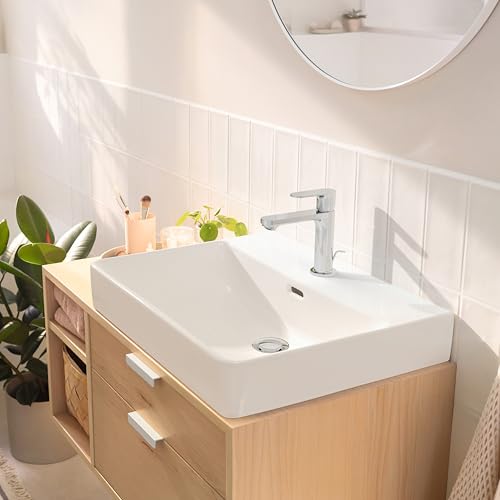 Chrome single-hole bathroom faucet with tall spout mounted on white sink above light wood vanity.