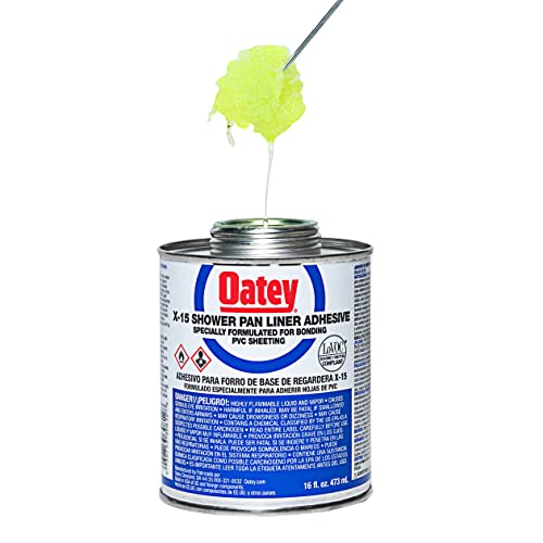 Oatey PVC solvent cement in metal can with brush applicator dispensing yellow-green adhesive.