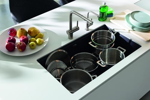 Black granite undermount kitchen sink with single bowl installed in white countertop, styled with cookware and faucet.