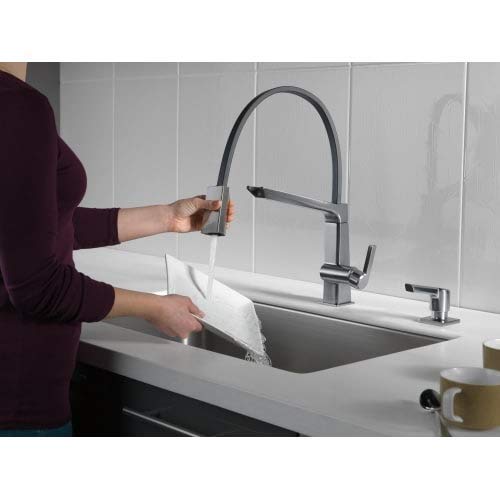 Stainless steel pull-down kitchen faucet with soap dispenser mounted on sink countertop.