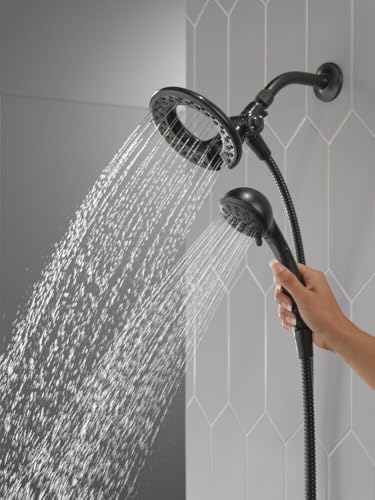 Chrome dual showerhead system with one large overhead head and one handheld head with hose, both dispensing water.