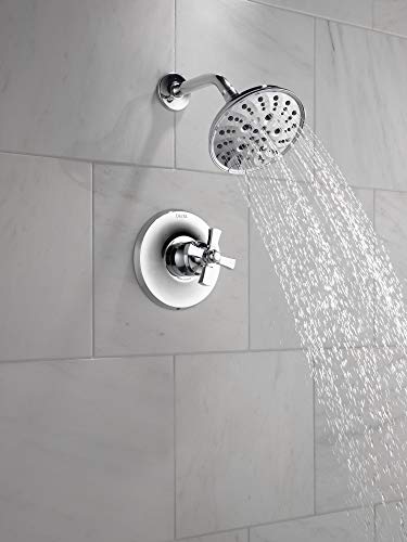 Chrome shower faucet with round trim plate and multi-spray showerhead mounted on tiled wall.