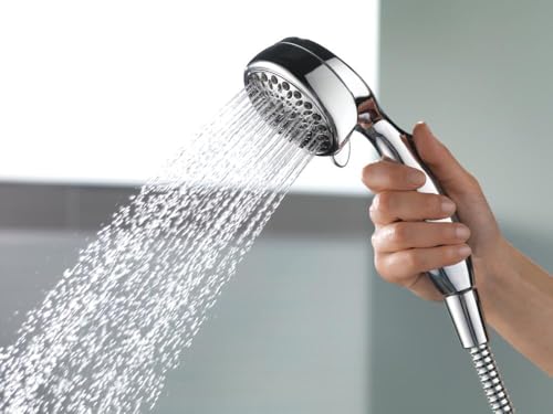 Chrome hand shower with black accent ring dispensing water spray, held in hand with flex hose visible.