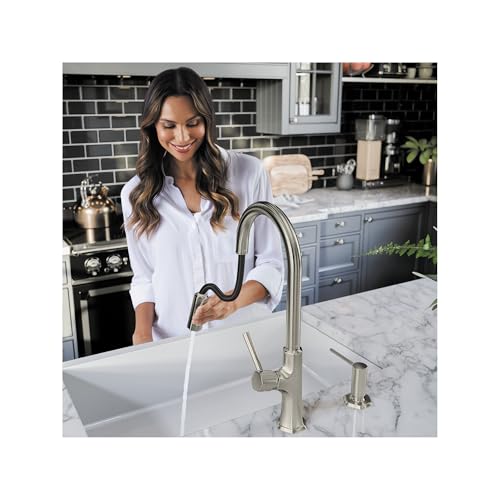 Steel optic high arc kitchen faucet with pull-down spray head mounted above white undermount sink.