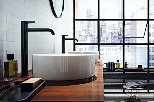 Matte black single-hole faucet with curved spout installed above white vessel sink in modern bathroom.
