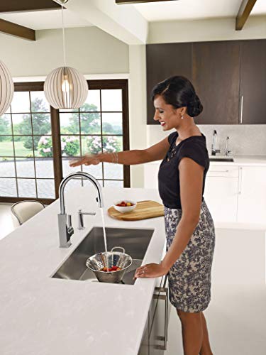 Stainless steel undermount kitchen sink installed in white countertop with pull-down faucet.