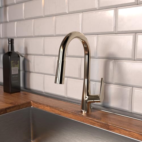 Polished nickel kitchen faucet with curved pull-down spout mounted on subway tile backsplash above wooden countertop.