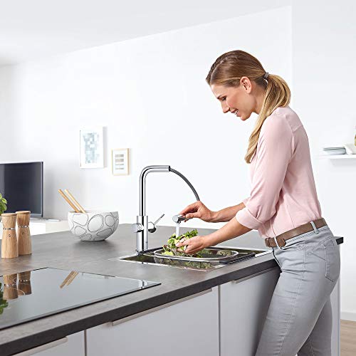Chrome single-handle pull-out kitchen faucet with curved spout installed above sink in modern kitchen.