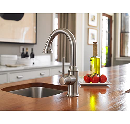 Stainless steel kitchen faucet with curved pull-down sprayer mounted above prep sink in kitchen countertop.