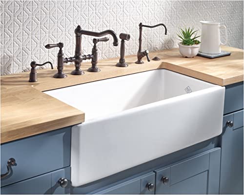 Unlacquered brass waste disposal control box with air switch button mounted under farmhouse sink countertop.