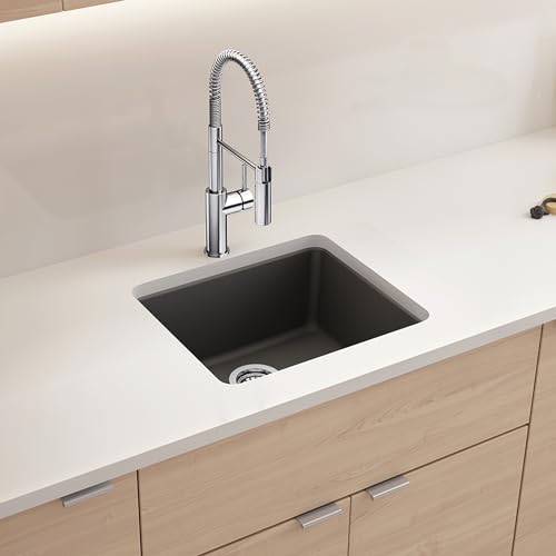 Cinder-colored single bowl undermount kitchen sink with chrome pull-down faucet mounted in white countertop above light wood 