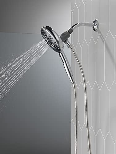 Chrome hand shower with magnetic dock mounted on wall tile, water spraying from shower head.