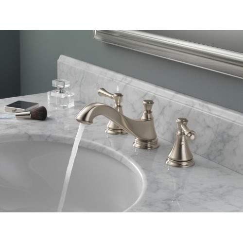 Stainless steel three-hole bathroom faucet with curved spout and lever handles mounted on marble countertop.