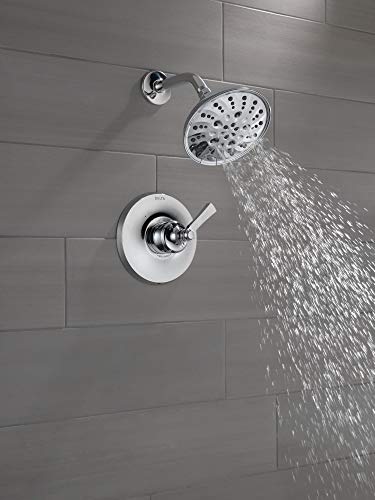 Chrome shower head with single lever handle mounted on gray tile wall, water streaming from perforated head.