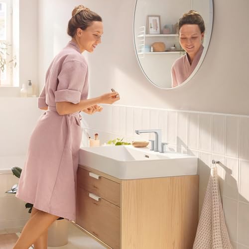 Chrome widespread bathroom faucet with curved spout and pop-up drain on white sink vanity.