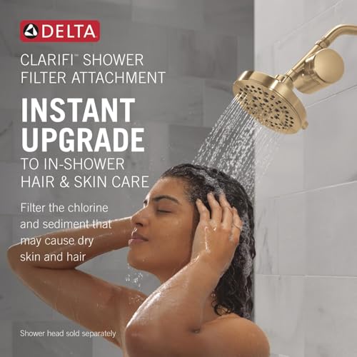 Champagne bronze shower filter attachment with perforated head and curved arm mounted on bathroom wall.