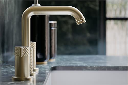 Antique gold widespread lavatory faucet with U-shaped spout and textured handles on bathroom sink.