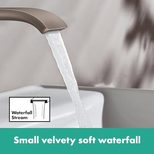 Brushed nickel widespread bathroom faucet with curved spout dispensing water in waterfall stream pattern.