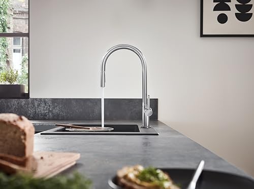 Brushed black chrome kitchen faucet with high arcing spout and pull-down spray head mounted on gray countertop.