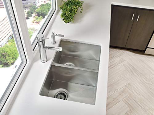 Stainless steel double bowl undermount kitchen sink installed in white countertop with chrome faucet.