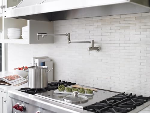 Wall-mounted stainless steel pot filler faucet with articulating arm above kitchen stovetop.