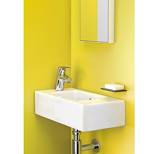 Chrome single-hole bathroom faucet with rounded spout mounted on white rectangular sink against yellow wall.