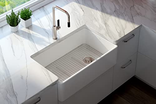 Stainless steel wire grid sink protector in white apron-front kitchen sink with bronze faucet.