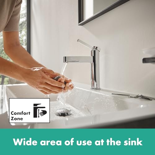 Brushed nickel single-hole faucet with tall spout dispensing water over hands at a white bathroom sink.