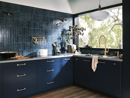 Brushed gold touchless kitchen faucet with pre-rinse sprayer installed above sink in blue cabinetry.