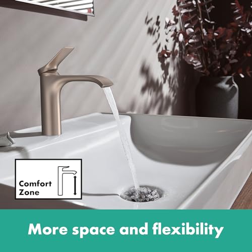 Brushed nickel widespread bathroom faucet with single lever handle mounted on white sink basin with water running.