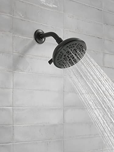 Matte black shower head with curved arm mounted on white tile wall, water streaming downward from perforated face.