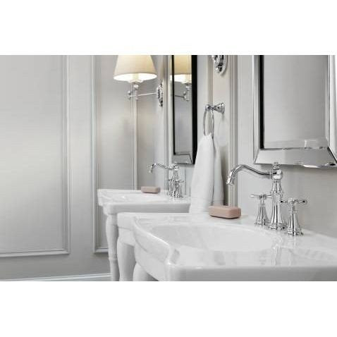 Polished nickel widespread bathroom faucet with cross handles installed on white vessel sink.