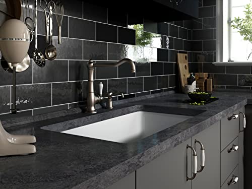 Satin black fireclay undermount kitchen sink installed in dark countertop with black subway tile backsplash.