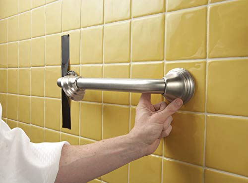 Chrome grab bar mounted on yellow tile wall with hand gripping it for stability.