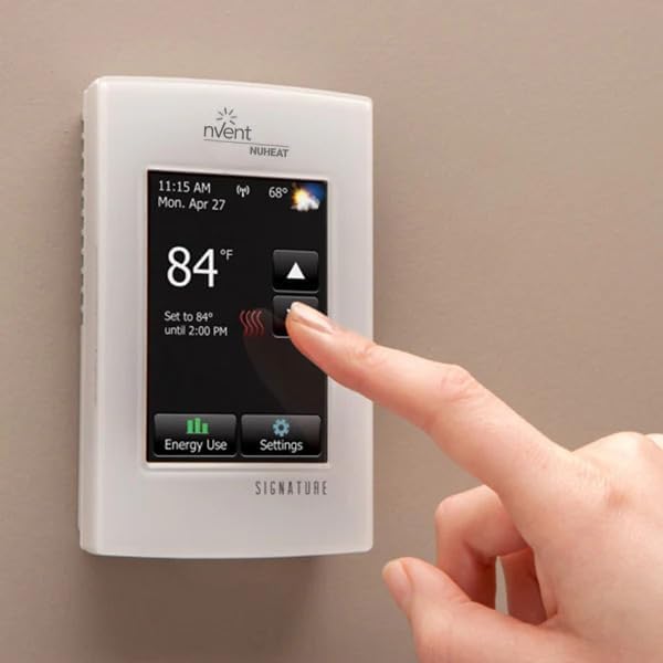 White Nuheat Signature floor heating thermostat with touchscreen displaying 84°F, time, and date, with a finger touching the 