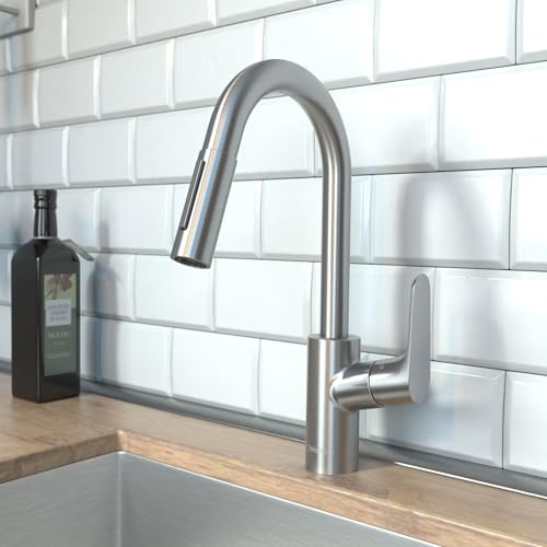 Stainless steel kitchen faucet with curved pull-down spout and single lever handle mounted on white subway tile backsplash.