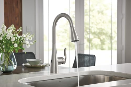 Stainless steel pull-down kitchen faucet with curved spout installed above undermount sink.