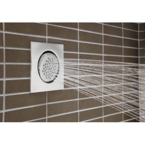 Chrome square body spray showerhead mounted on tiled wall with water spray pattern visible.