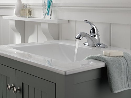 Chrome single-handle bathroom faucet with curved spout mounted on white sink in dark vanity.