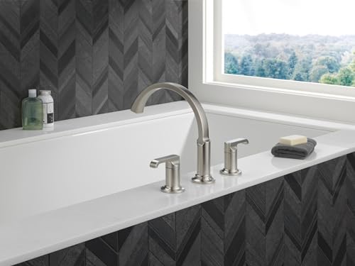 Stainless steel roman tub faucet with curved spout and lever handles mounted on white bathtub rim.
