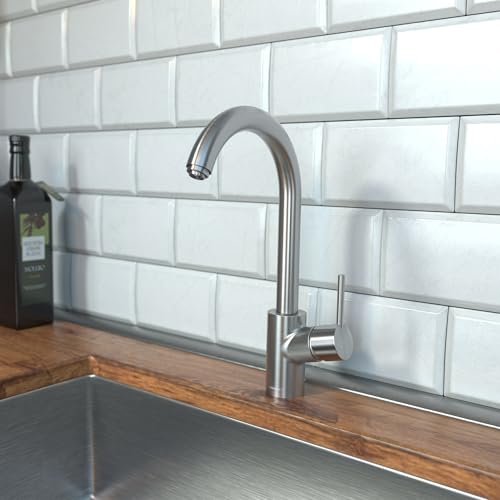 Stainless steel kitchen faucet with curved spout and pull-down spray head mounted above a sink against white subway tile back