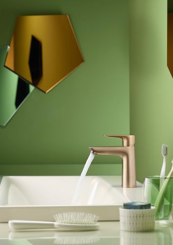 Brushed bronze single-hole bathroom faucet with curved spout over white sink, water running, against green wall.