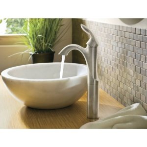 Brushed nickel single-handle bathroom faucet with curved spout installed above a white ceramic vessel sink.