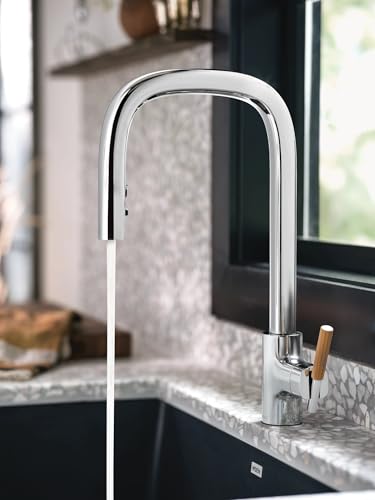Chrome kitchen faucet with tall curved spout and pulldown spray head over sink.
