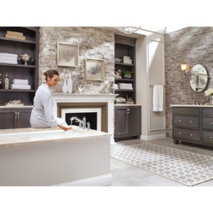 Chrome two-handle high arc faucet with curved spout mounted on white bathtub rim in bathroom setting.