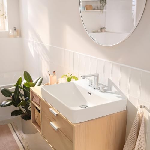 Matte black widespread bathroom faucet with two handles mounted on white rectangular sink in light wood vanity.